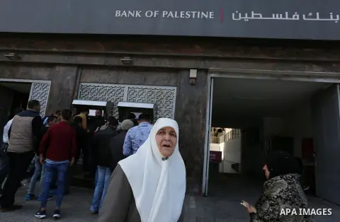Palestinian employees paid by the Palestinian Authority wait to receive their salaries from an ATM, outside a Bank in Gaza City April 5, 2017. The salaries of Palestinian employees in Gaza strip have been reduced by abou...