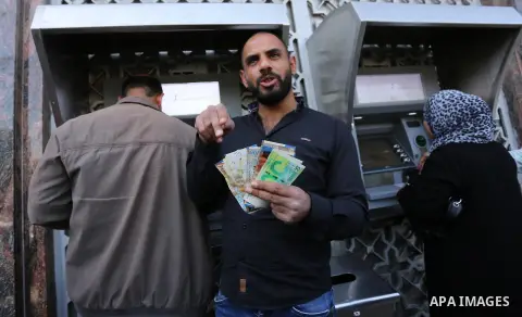 Palestinian employees paid by the Palestinian Authority wait to receive their salaries from an ATM, outside a Bank in Gaza City April 5, 2017. The salaries of Palestinian employees in Gaza strip have been reduced by abou...