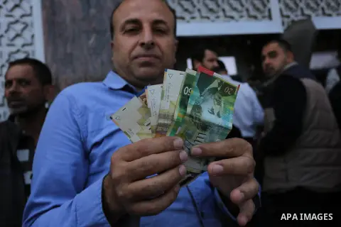 Palestinian employees paid by the Palestinian Authority wait to receive their salaries from an ATM, outside a Bank in Gaza City April 5, 2017. The salaries of Palestinian employees in Gaza strip have been reduced by abou...