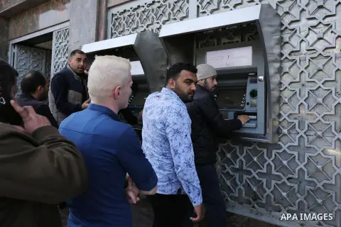 Palestinian employees paid by the Palestinian Authority wait to receive their salaries from an ATM, outside a Bank in Gaza City April 5, 2017. The salaries of Palestinian employees in Gaza strip have been reduced by abou...