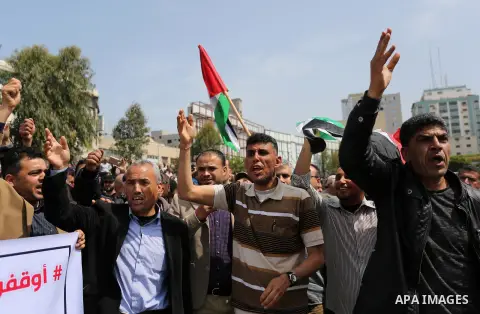 Palestinians, employed by the Palestinian Authority, chant slogans and wave placards during a demonstration against the decision to reduce their salaries in Gaza City on April 8, 2017. Photo by Ashraf Amra