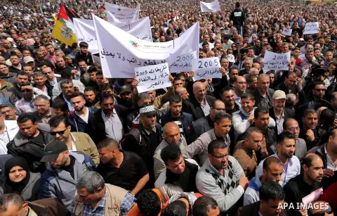 Palestinians, employed by the Palestinian Authority, chant slogans and wave placards during a demonstration against the decision to reduce their salaries in Gaza City on April 8, 2017. Photo by Ashraf Amra