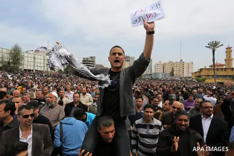 A Palestinian Authority employee holds a sign and chants slogans during a demonstration against the decision to reduce their salaries in Gaza City on April 8, 2017. Photo by Ashraf Amra
