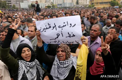 Palestinians, employed by the Palestinian Authority, chant slogans and wave placards during a demonstration against the decision to reduce their salaries in Gaza City on April 8, 2017. Photo by Ashraf Amra
