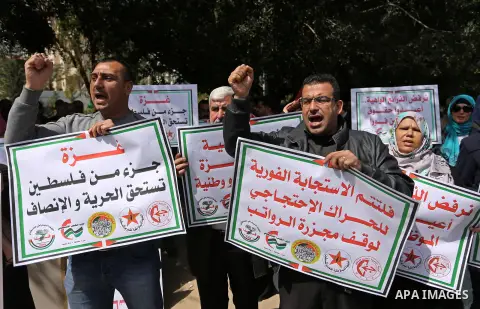 Palestinians employed by the Palestinian Authority, chant slogans and wave placards during a demonstration against the decision to reduce their salaries in Gaza City on April 11, 2017. Photo by Ashraf Amra