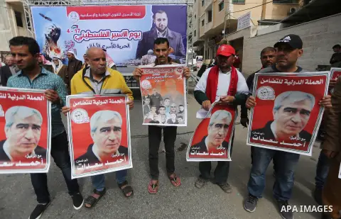 Palestinians hold placards during a protest to show solidarity with Palestinian prisoners held in Israeli Jails, in front of Red cross office in Gaza city, on April 17, 2017. Photo by Mohammed Asad
