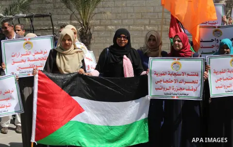 Palestinians hold placards during a demonstration against the decision to reduce their salaries in Gaza City on April 18, 2017. Photo by Mohammed Asad