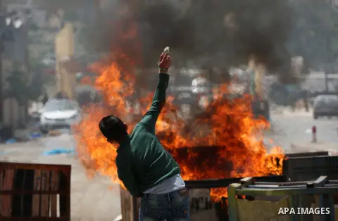 A Palestinian protester dodges teargas cannisters during clashes with Israeli forces in the West Bank village of Beita, southeast of Nablus city, after a protest took place following Friday prayers in solidarity with Pal...