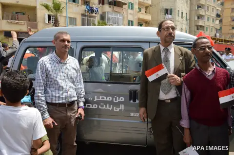 Egypians stand next to a mini-bus before Mona El Sayed, an Egyptian woman known in media as "girl cart" receives it which was funded by “Tahya Masr” (Long Live Egypt) fund in Cairo, Egypt, on April 22, 2017. Just days af...