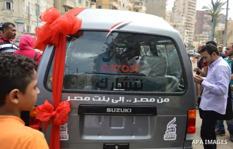Egypians stand next to a mini-bus before Mona El Sayed, an Egyptian woman known in media as "girl cart" receives it which was funded by “Tahya Masr” (Long Live Egypt) fund in Cairo, Egypt, on April 22, 2017. Just days af...
