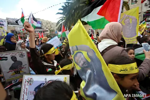 Palestinian protesters wave flags bearing the portrait of prominent prisoner and popular leader Marwan Barghouti during a demonstration in solidarity with Palestinian prisoners on hunger strike in Israeli jails, in the W...