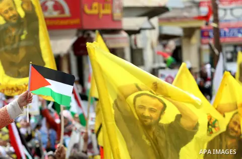 Palestinian protesters wave flags bearing the portrait of prominent prisoner and popular leader Marwan Barghouti during a demonstration in solidarity with Palestinian prisoners on hunger strike in Israeli jails, in the W...