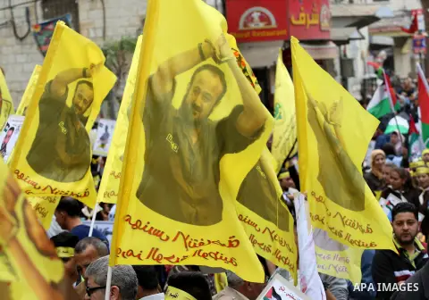 Palestinian protesters wave flags bearing the portrait of prominent prisoner and popular leader Marwan Barghouti during a demonstration in solidarity with Palestinian prisoners on hunger strike in Israeli jails, in the W...