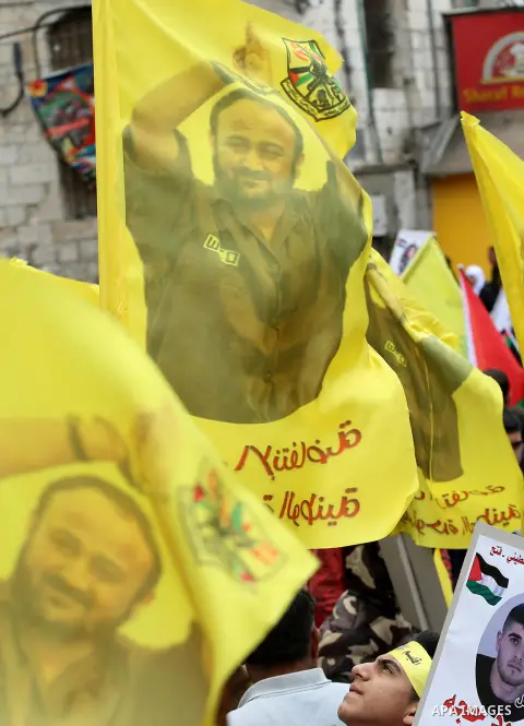 Palestinian protesters wave flags bearing the portrait of prominent prisoner and popular leader Marwan Barghouti during a demonstration in solidarity with Palestinian prisoners on hunger strike in Israeli jails, in the W...