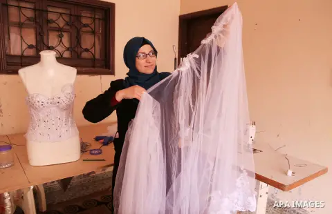 Manar Tafesh, 30, a Palestinian fashion designer works on knitting wedding dresses at her house with her husband to help him after he lost his work as tailor in the Palestinian territory occupied, in Gaza city on Feb. 14...