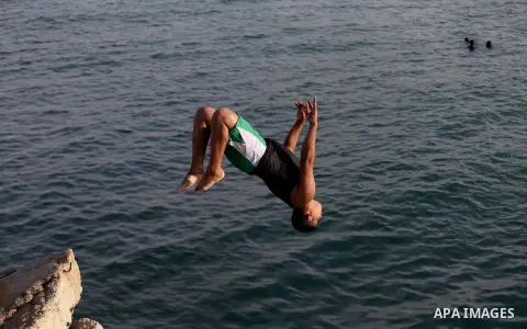 A Palestinian youth jumps into the Mediterranean Sea at the Gaza seaport in Gaza City on May 5, 2017. Photo by Mohammed Asad