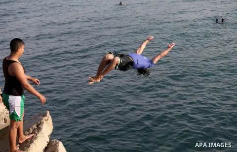 A Palestinian youth jumps into the Mediterranean Sea at the Gaza seaport in Gaza City on May 5, 2017. Photo by Mohammed Asad