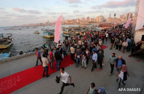 Palestinians walk on a red carpet during the 3rd Annual Red Carpet Festival for Human Rights Films at the Gaza seaport, on May 12, 2017. The Red Carpet Festival is held in the Gaza Strip this year for the third year in a...