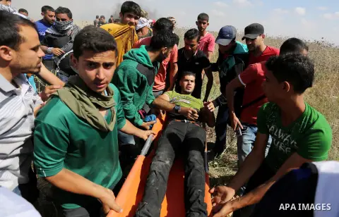 A Palestinian protester is evacuated after he was wounded during clashes with Israeli security forces following a protest against the blockade on Gaza Strip, near Nahal Oz crossing east of Gaza City on May 19, 2017. Phot...