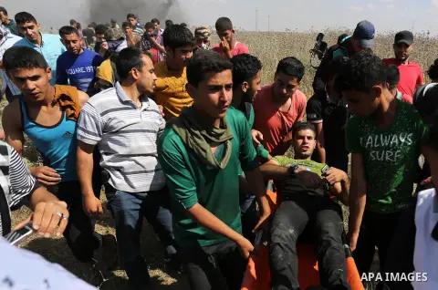 A Palestinian protester is evacuated after he was wounded during clashes with Israeli security forces following a protest against the blockade on Gaza Strip, near Nahal Oz crossing east of Gaza City on May 19, 2017. Phot...