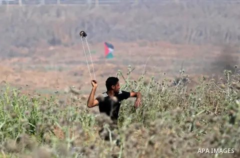 A Palestinian protester uses a slingshot to hurl stones towards Israeli security forces during clashes following a protest against the blockade on Gaza Strip, near Nahal Oz crossing east of Gaza City on May 19, 2017. Pho...
