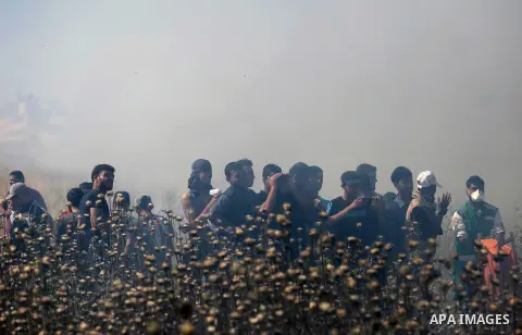 Palestinians protesters take cover from tear gas fired by Israeli security forces during clashes following a protest against the blockade on Gaza Strip, near Nahal Oz crossing east of Gaza City on May 19, 2017. Photo by...