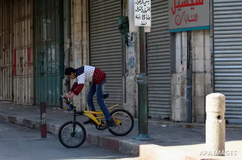 A Palestinian boy rides his bicycle in front of closed shops during a general strike in support of Palestinian prisoners on hunger strike in Israeli jails, in the market in the Old City of the West Bank town of Nablus, o...