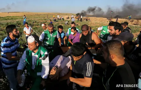 Palestinian protesters carry a wounded man during clashes with Israeli security forces following a demonstration against the blockade on the Gaza Strip, near the border fence east of Jabalia refugee camp on June 5, 2017....