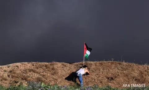 A Palestinian protester waves the national during clashes with Israeli security forces following a protest near the border fence east of Jabalia refugee camp, against the blockade on the Gaza Strip on June 5, 2017. Photo...
