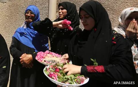 Mourners throw flowers at the body of a 25-year-old Palestinian Fadi al-Najjar who was killed by Israeli fire in the Gaza Strip during clashes with Israeli sceurity forces at the border fence the previous day, during his...