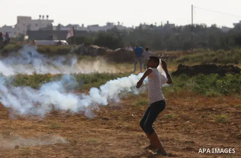 A Palestinian protester throws a tear gas canister towards Israeli security forces during clashes following a demonstration against the blockade on the Gaza Strip, near the border fence east of Jabalia refugee camp on Ju...