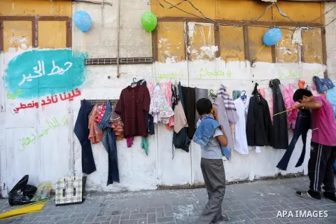 Palestinian boys look at second hand clothes attached on the wall at street for poor people, on the Muslim holy fasting month of Ramadan, on Gaza city on June 14, 2017. Ramadan is sacred to Muslims because it is during t...