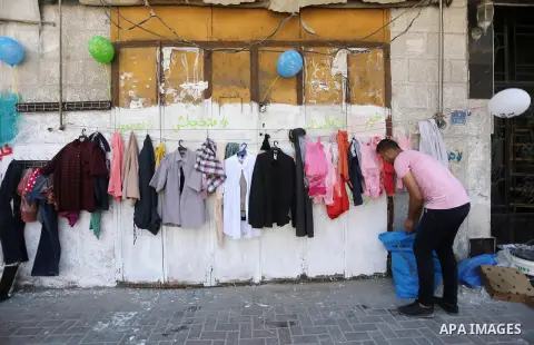 A Palestinian youth attaches second hand clothes on the wall at street for poor people, on the Muslim holy fasting month of Ramadan, on Gaza city on June 14, 2017. Ramadan is sacred to Muslims because it is during that m...