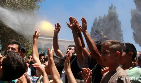 Palestinian Muslim worshippers are sprinkled with water to cool down from the soaring heat ahead of the second Friday prayers of the Muslim holy month of Ramadan in front of the Dome of the Rock at Jerusalem's al-Aqsa mo...