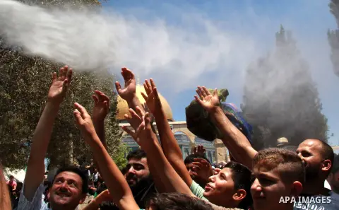 Palestinian Muslim worshippers are sprinkled with water to cool down from the soaring heat ahead of the second Friday prayers of the Muslim holy month of Ramadan in front of the Dome of the Rock at Jerusalem's al-Aqsa mo...