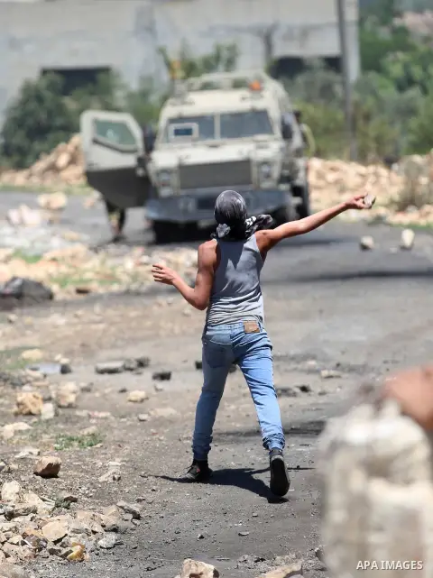 A Palestinian protester hurls stones towards Israeli security forces during clashes following a demonstration against the expropriation of Palestinian land by Israel in the village of Kfar Qaddum, near Nablus, in the occ...