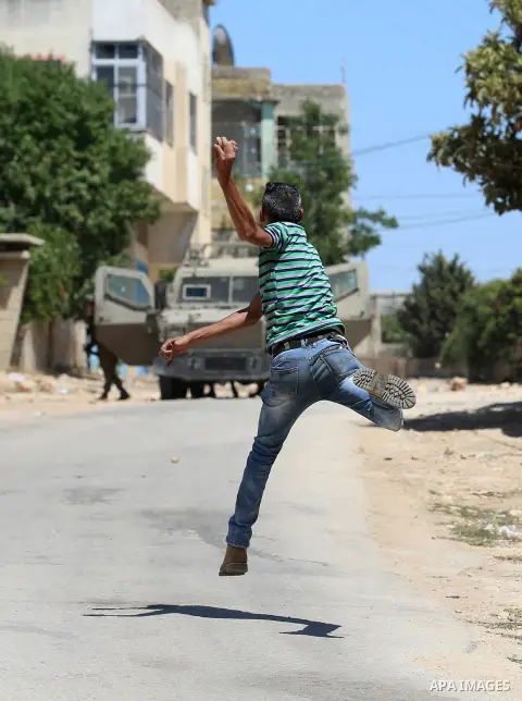 A Palestinian protester hurls stones towards Israeli security forces during clashes following a demonstration against the expropriation of Palestinian land by Israel in the village of Kfar Qaddum, near Nablus, in the occ...