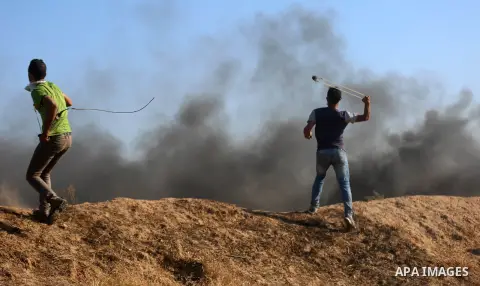 A Palestinian protester uses a slingshot to hurl stones towards Israeli security forces during clashes following a demonstration against the blockade on the Gaza Strip, near the border fence east of Jabalia refugee camp...