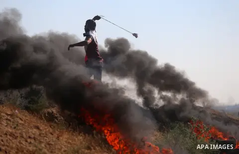 A Palestinian protester uses a slingshot to hurl stones towards Israeli security forces during clashes following a demonstration against the blockade on the Gaza Strip, near the border fence east of Jabalia refugee camp...