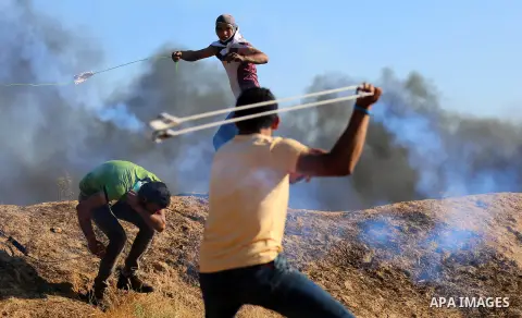 A Palestinian protester uses a slingshot to hurl stones towards Israeli security forces during clashes following a demonstration against the blockade on the Gaza Strip, near the border fence east of Jabalia refugee camp...