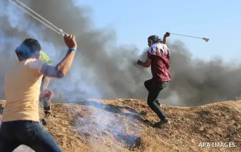 A Palestinian protester uses a slingshot to hurl stones towards Israeli security forces during clashes following a demonstration against the blockade on the Gaza Strip, near the border fence east of Jabalia refugee camp...