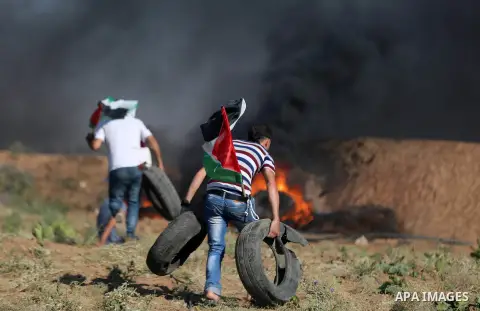 Palestinian protesters take cover during clashes with Israeli security forces following a demonstration against the blockade on the Gaza Strip, near the border fence east of Jabalia refugee camp on June 16, 2017. Photo b...