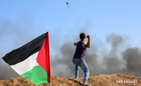 A Palestinian protester uses a slingshot to hurl stones towards Israeli security forces during clashes following a demonstration against the blockade on the Gaza Strip, near the border fence east of Jabalia refugee camp...
