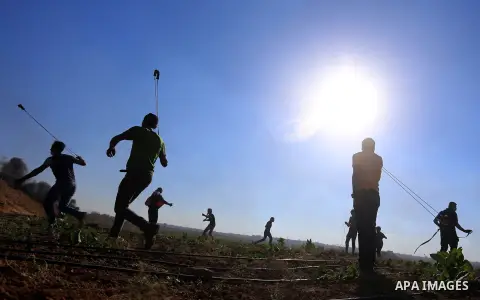 A Palestinian protester uses a slingshot to hurl stones towards Israeli security forces during clashes following a demonstration against the blockade on the Gaza Strip, near the border fence east of Jabalia refugee camp...