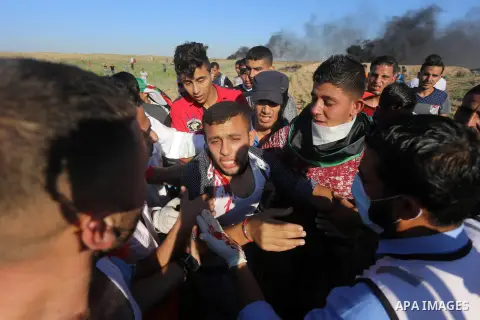 Palestinian protesters carry a wounded man during clashes with Israeli security forces following a demonstration against the blockade on the Gaza Strip, near the border fence east of Jabalia refugee camp on June 16, 2017...