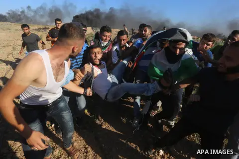 Palestinian protesters carry a wounded man during clashes with Israeli security forces following a demonstration against the blockade on the Gaza Strip, near the border fence east of Jabalia refugee camp on June 16, 2017...