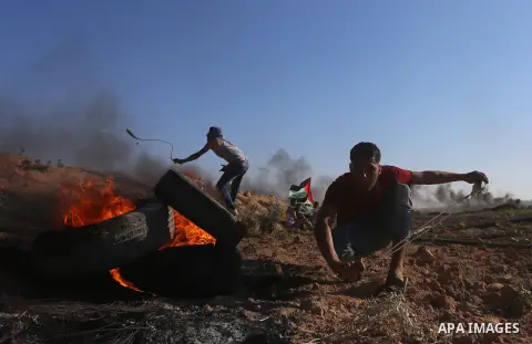 Palestinian protesters take cover during clashes with Israeli security forces following a demonstration against the blockade on the Gaza Strip, near the border fence east of Jabalia refugee camp on June 16, 2017. Photo b...