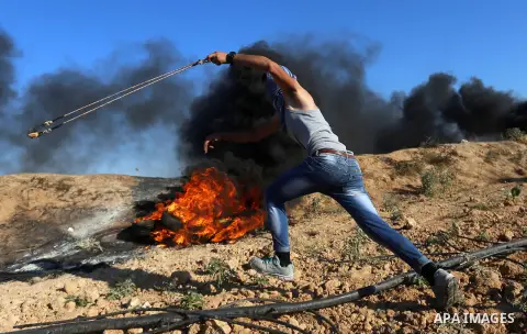 Palestinian protesters take cover during clashes with Israeli security forces following a demonstration against the blockade on the Gaza Strip, near the border fence east of Jabalia refugee camp on June 16, 2017. Photo b...