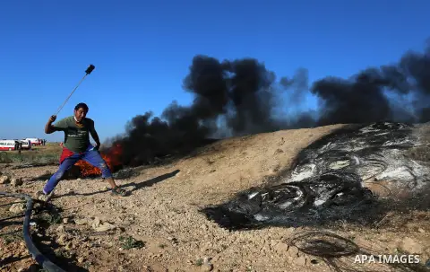 Palestinian protesters take cover during clashes with Israeli security forces following a demonstration against the blockade on the Gaza Strip, near the border fence east of Jabalia refugee camp on June 16, 2017. Photo b...