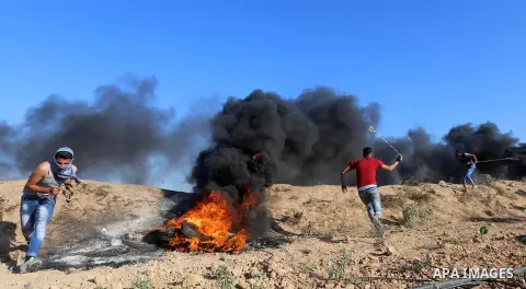 Palestinian protesters take cover during clashes with Israeli security forces following a demonstration against the blockade on the Gaza Strip, near the border fence east of Jabalia refugee camp on June 16, 2017. Photo b...